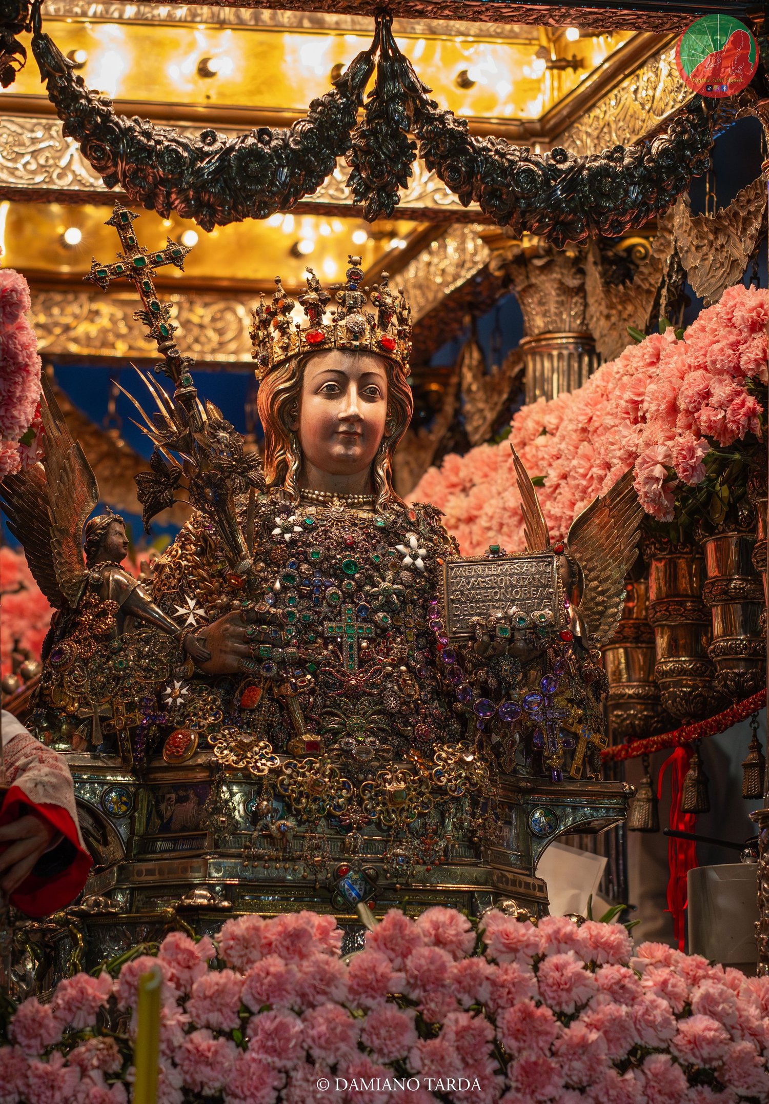 Il Busto di Sant'Agata sul fercolo tra garofani rosa e decorazioni dorate.