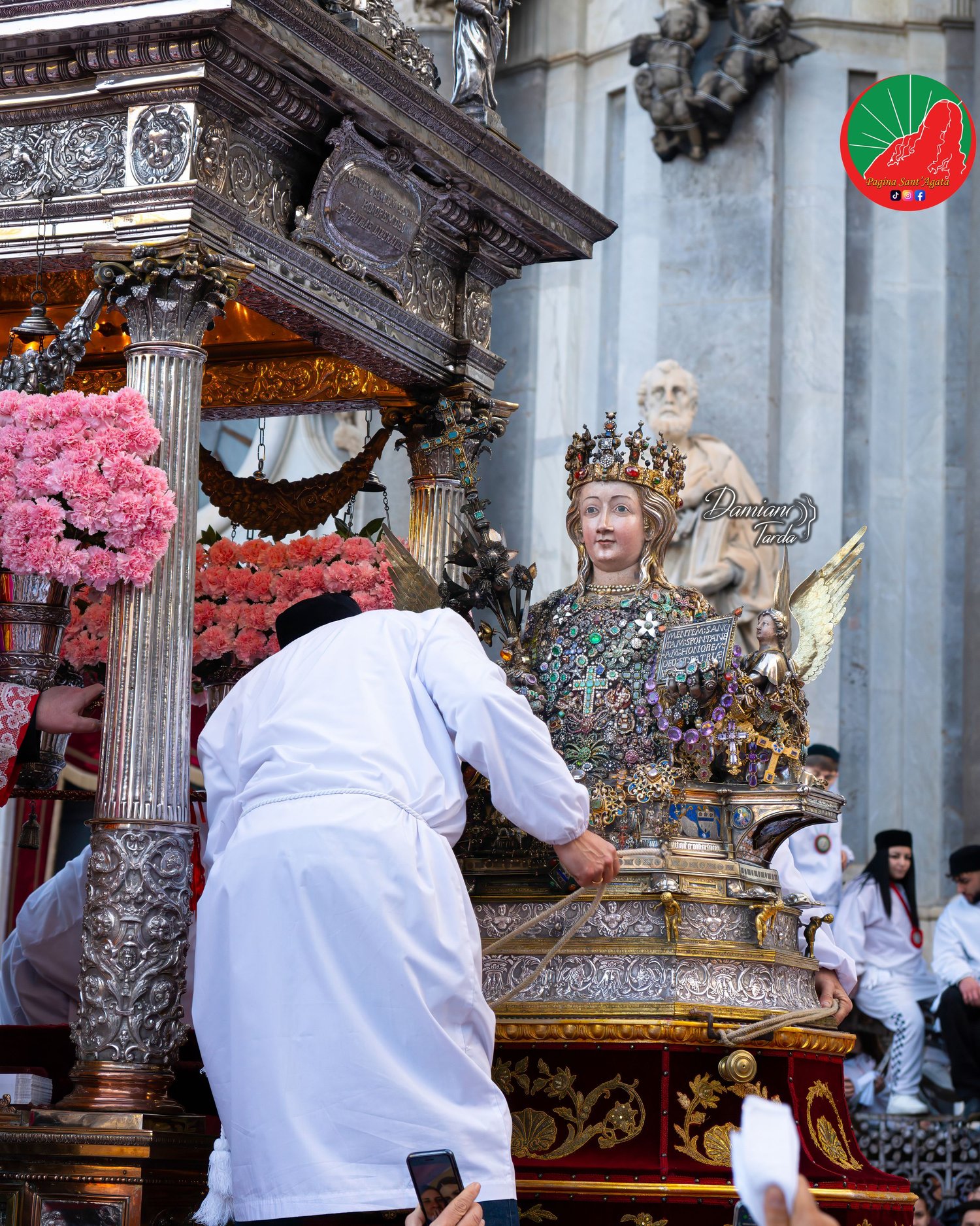 Un devoto accanto al Busto di Sant'Agata sul fercolo ornato di garofani rosa.